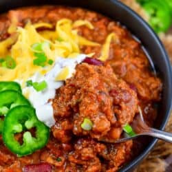 scooping out some beef chili from the bowl with a spoon.