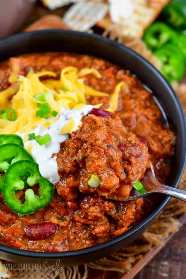 scooping out some beef chili from the bowl with a spoon.