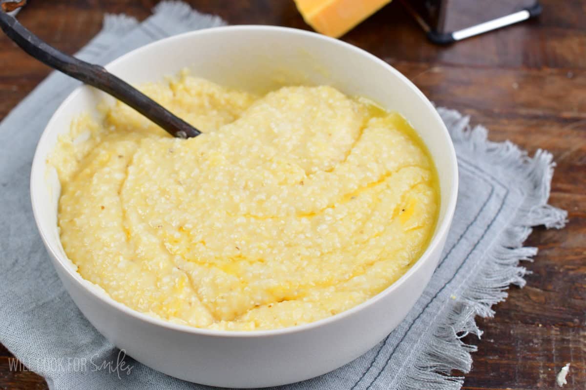 stirred butter cheesy grits in a bowl with a spoon.