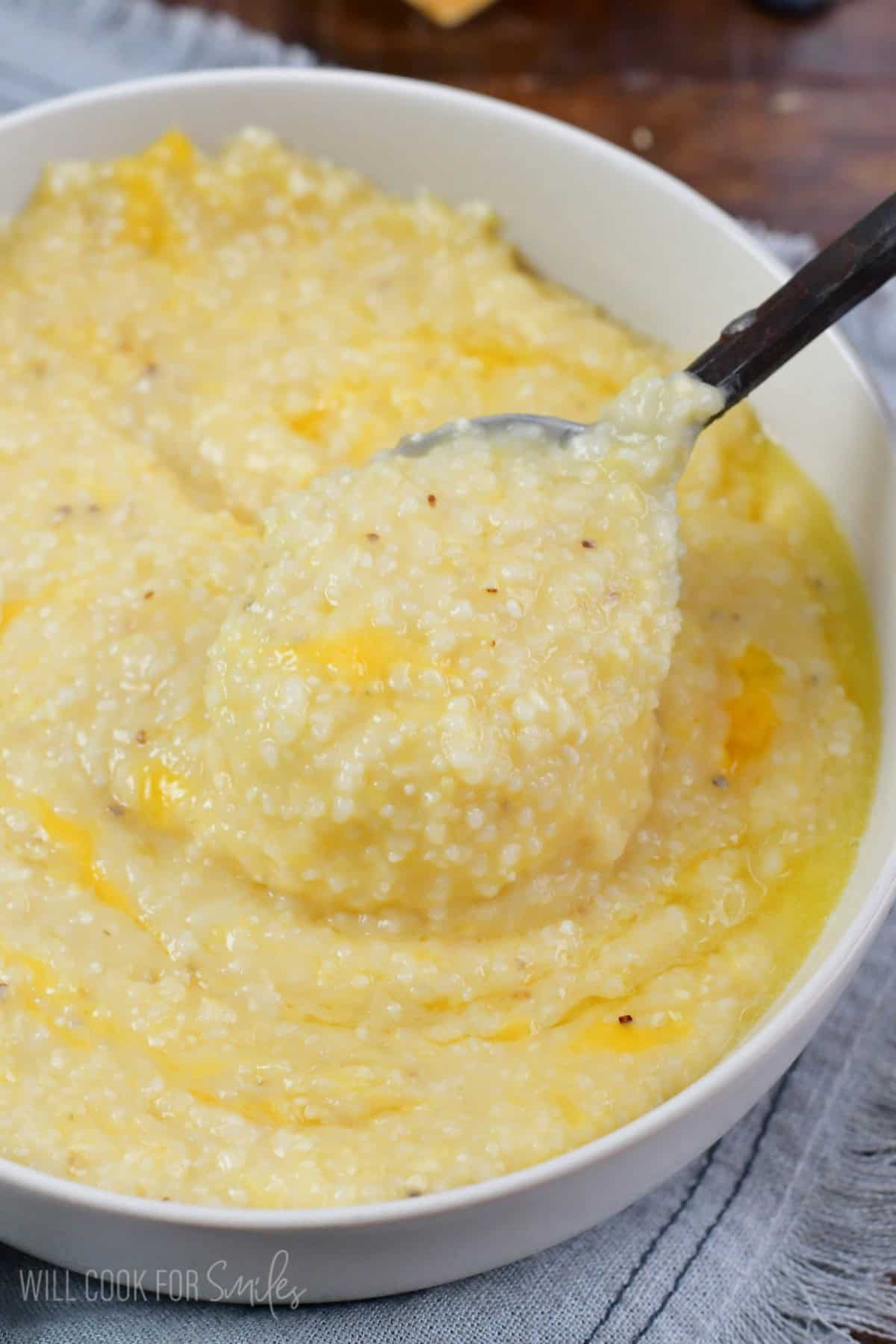 spooning some cheesy grits out of a bowl.