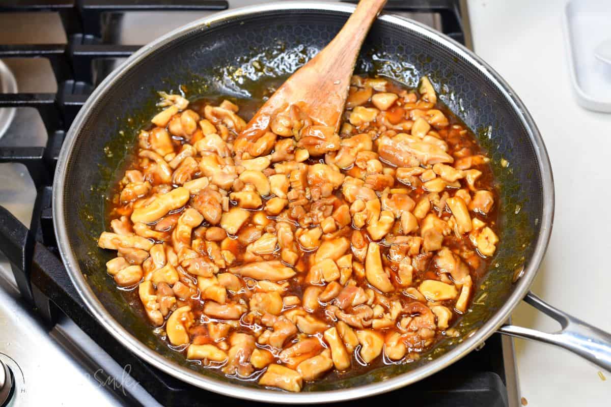 stirring cooked chicken pieces in teriyaki sauce.