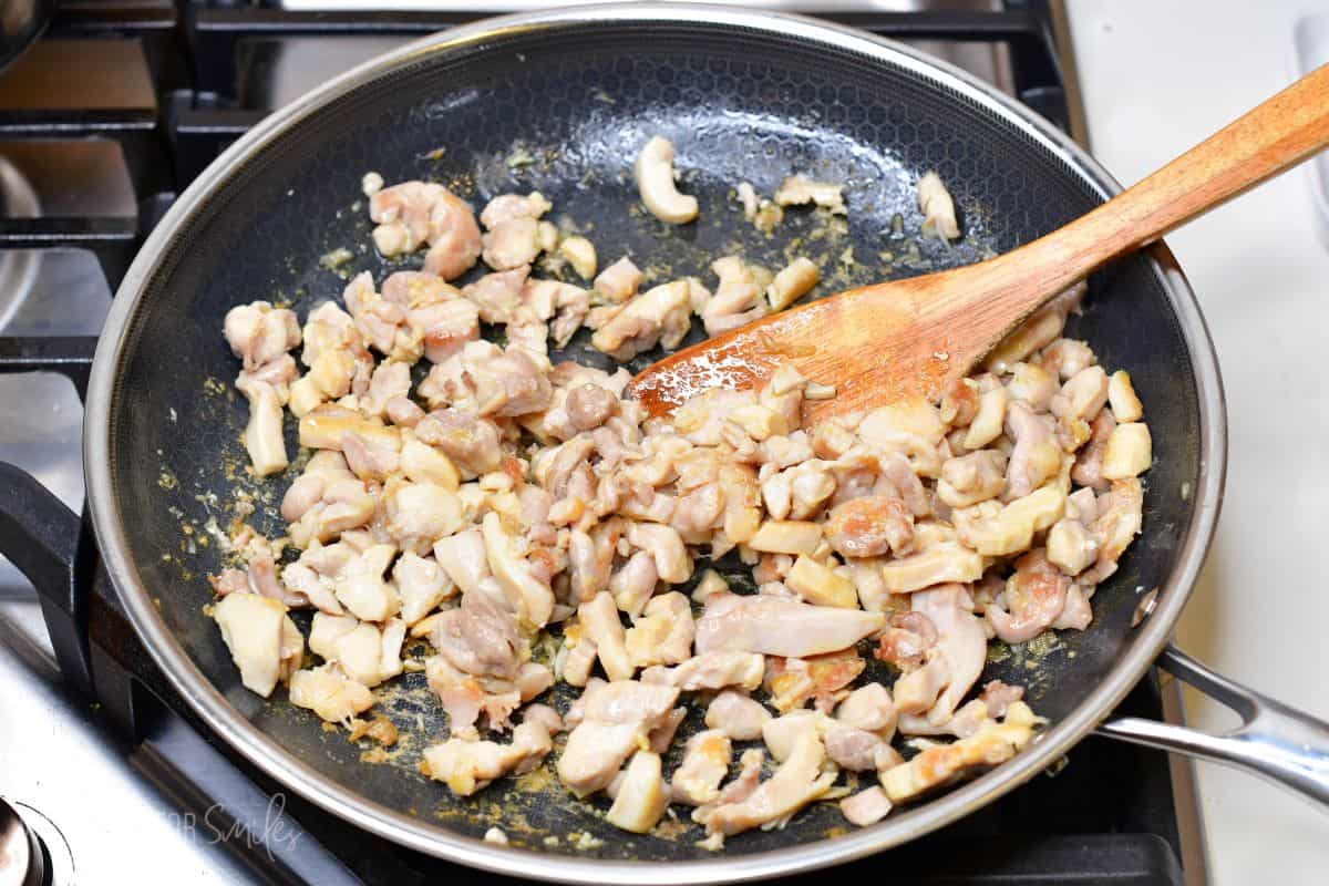 stirring browned chicken pieces in the pan.