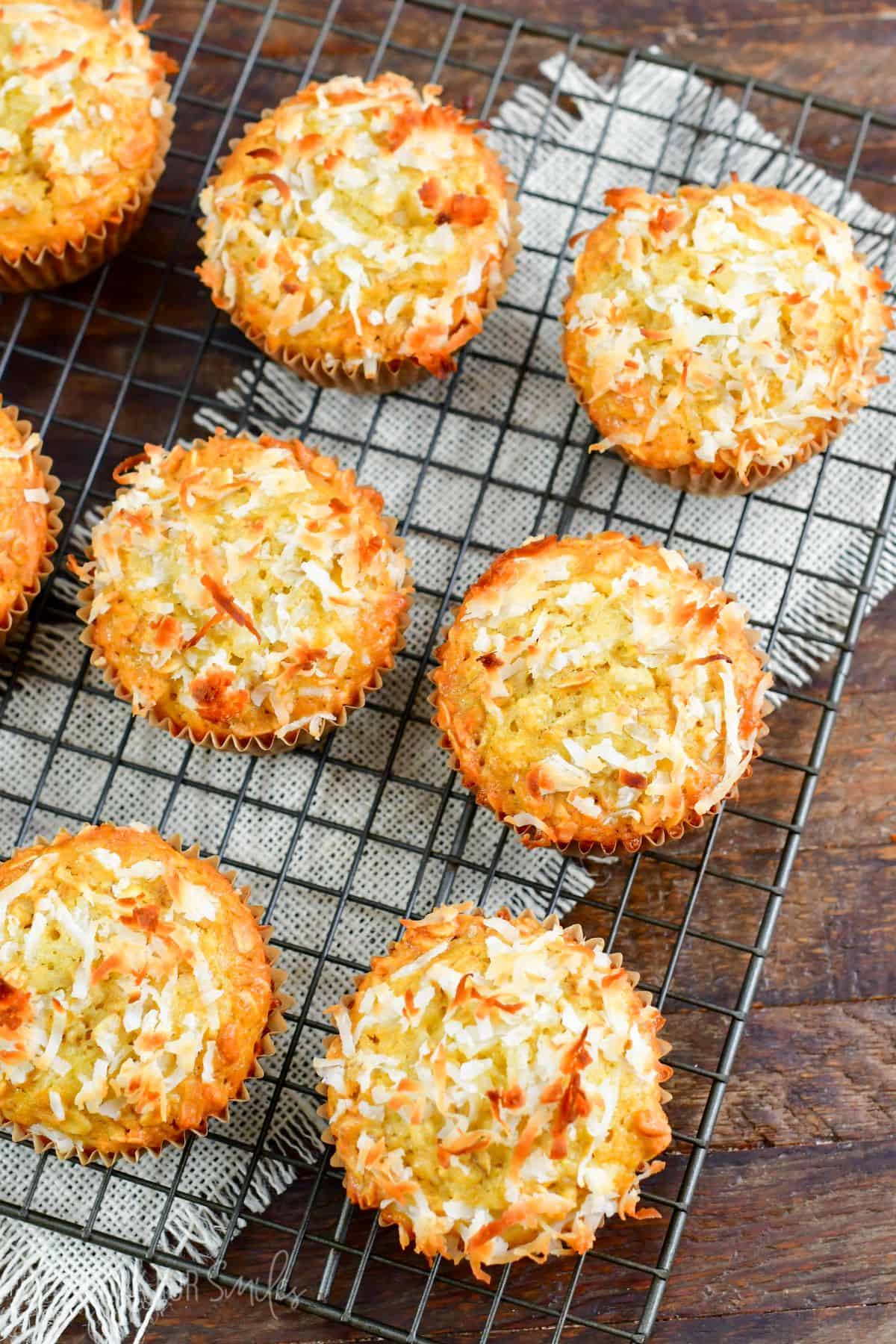 Coconut Oat Muffins on a wire rack on a wood surface with a white burlap cloth under it.