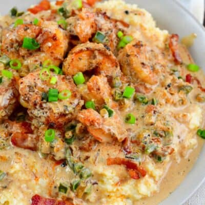 creamy Cajun shrimp and grits in a grey bowl topped with green onion.