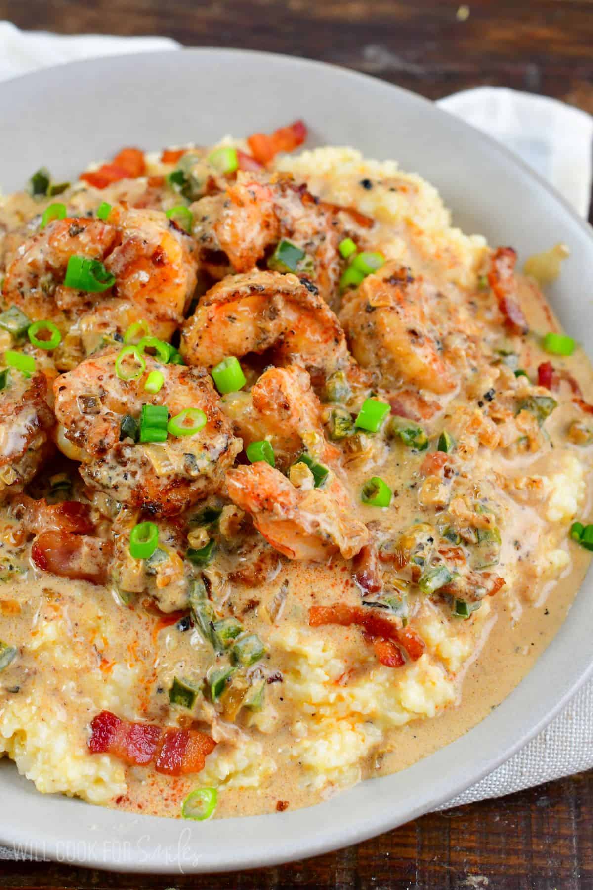 creamy Cajun shrimp and grits in a grey bowl topped with green onion.