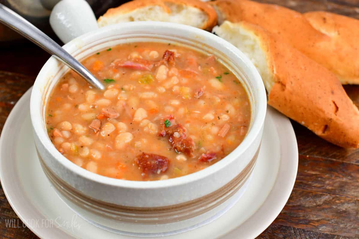 ham and bean soup in a light bowl with bead next to it.