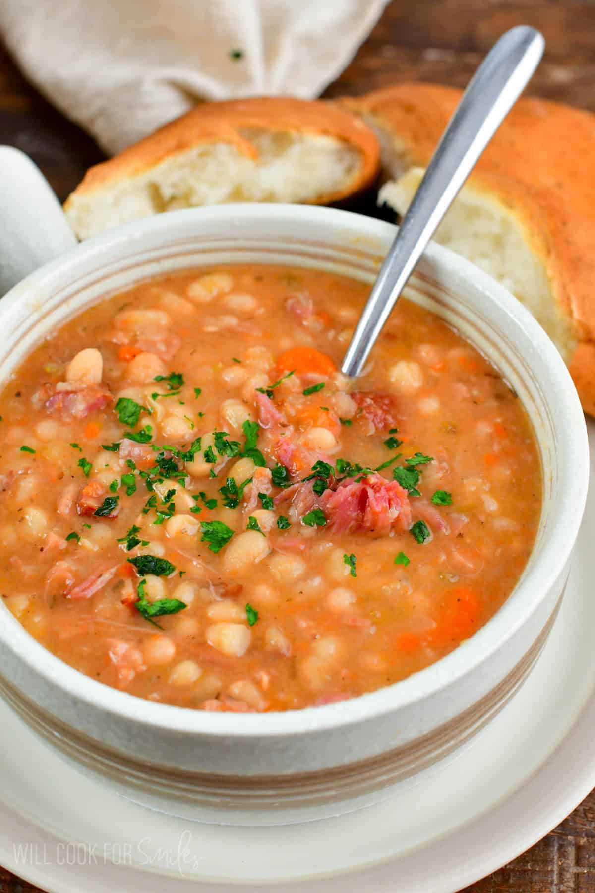 ham and bean soup in a light color bowl with a spoon in it.