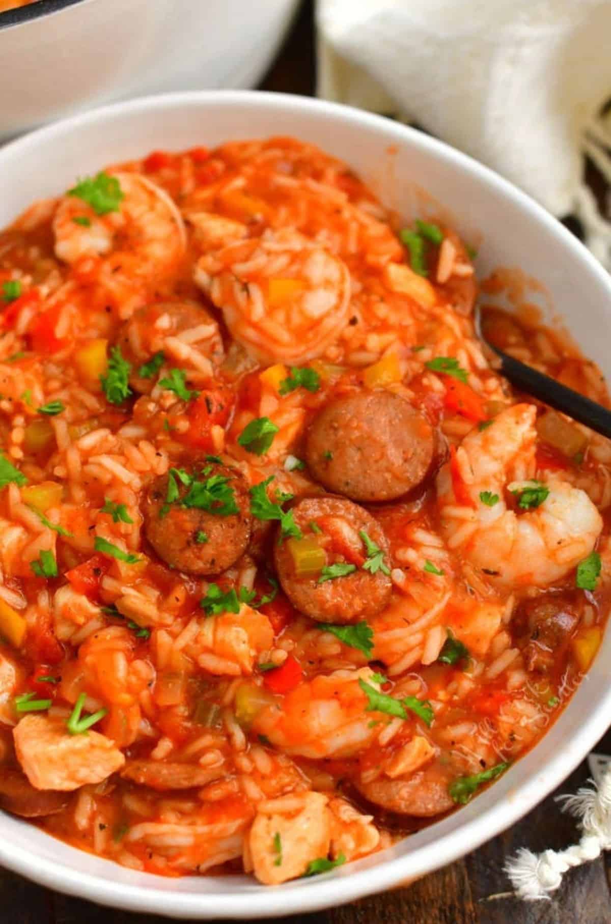 jambalaya in a bowl sprinkled with a little parsley a spoon in the bowl.