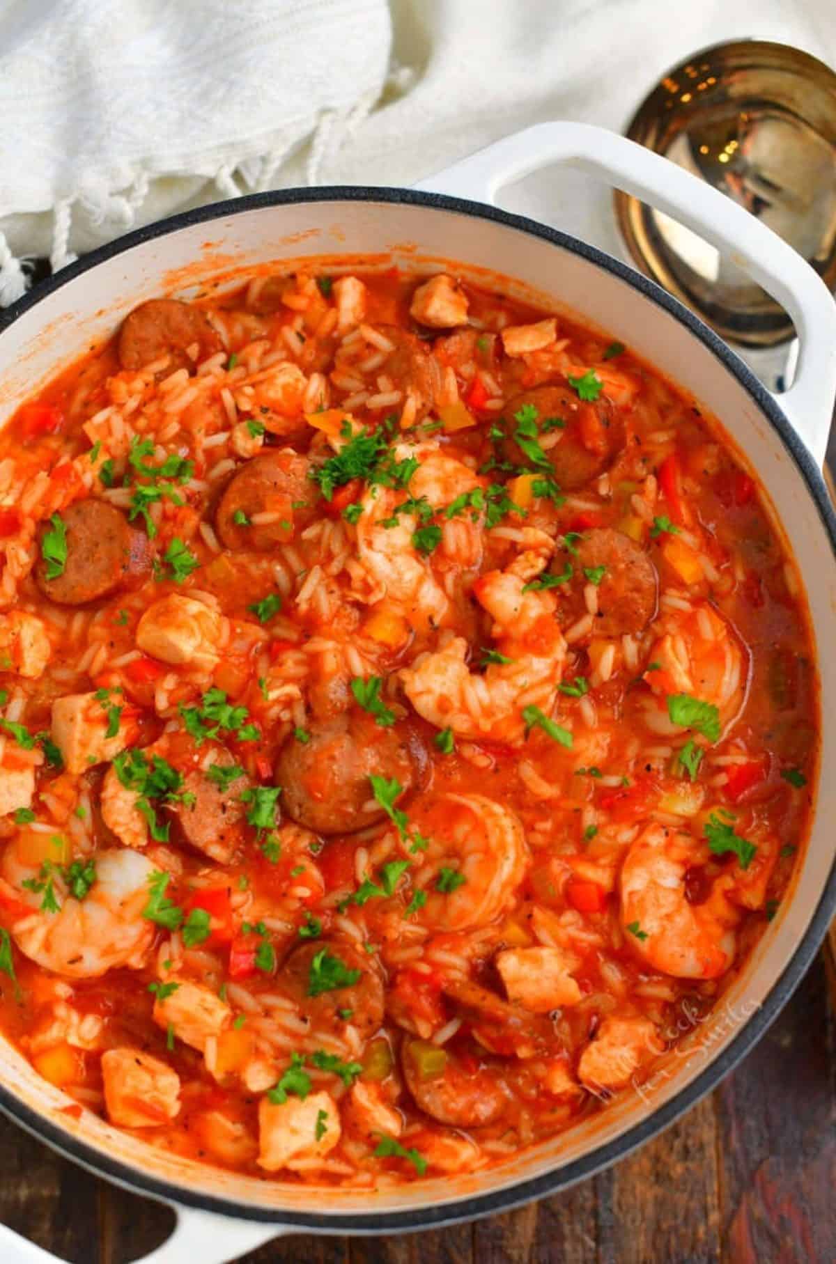 jambalaya in a white Dutch oven pot with a ladle next to the pot.