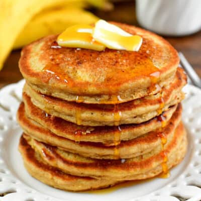 stack of blender oatmeal pancakes topped with butter and dripping maple syrup on the side.