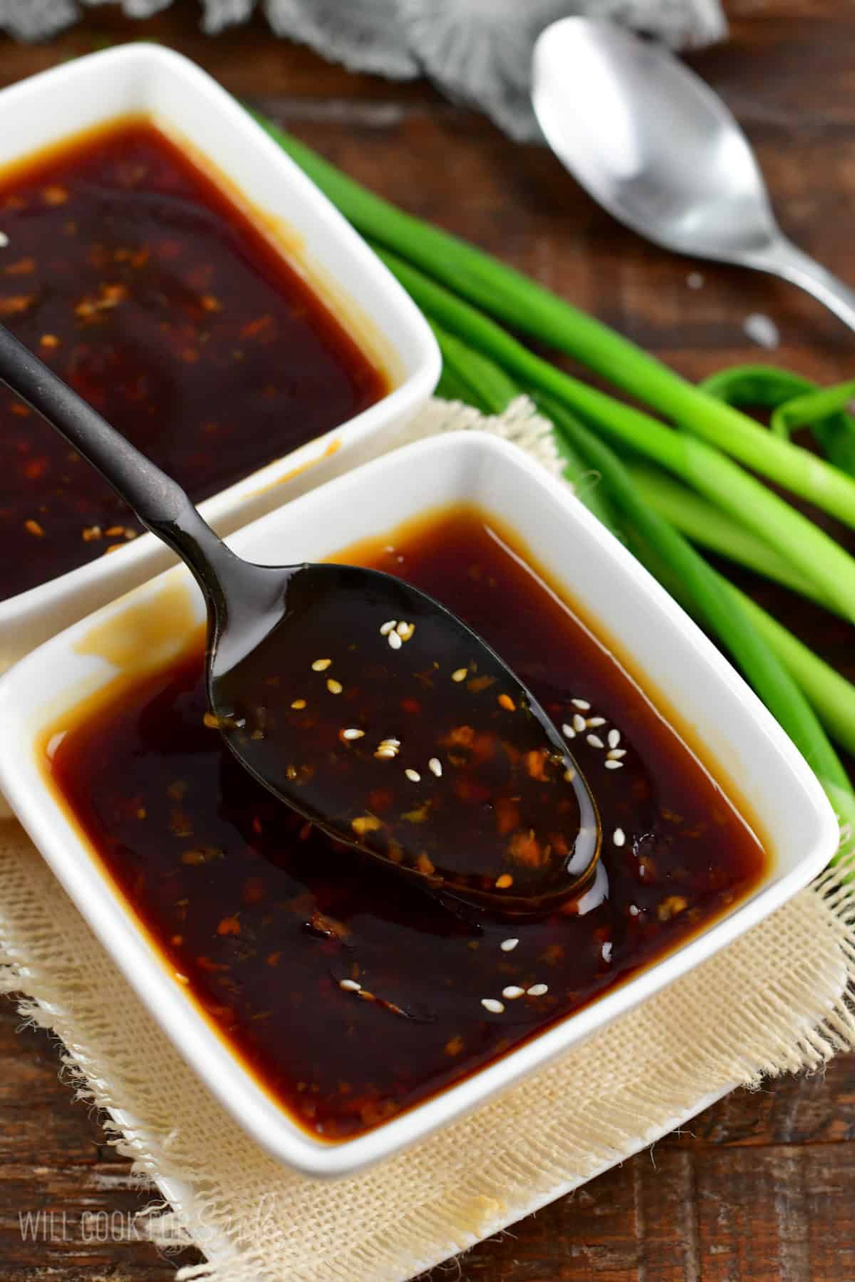 spooning out some teriyaki sauce from a bowl.