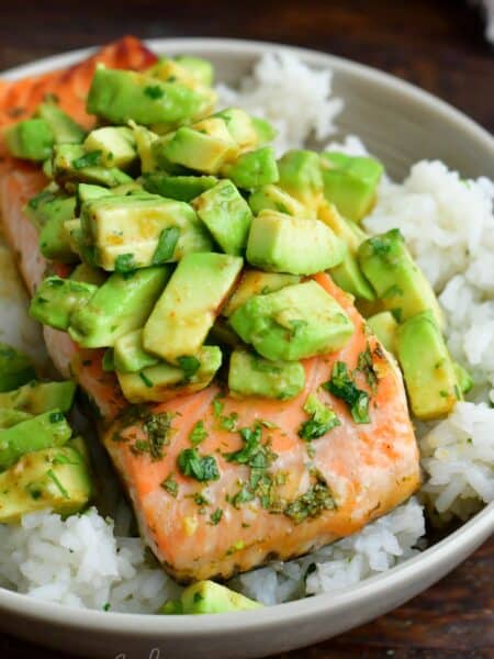 baked salmon over the bowl of rice topped with avocado topping.