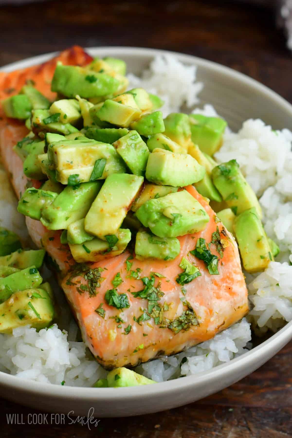 baked salmon over the bowl of rice topped with avocado topping.