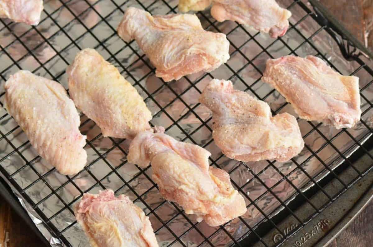 un cooked chicken wings with seasoning on a wire rack.