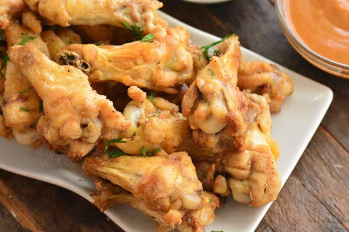 Baked chicken wings on a plate on a wood surface.