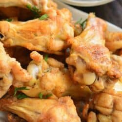 Baked chicken wings on a plate stacked up.