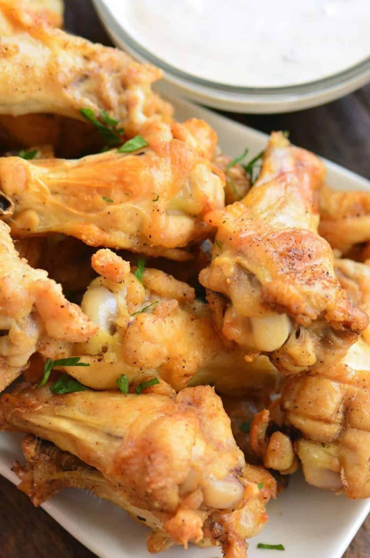 Baked chicken wings on a plate stacked up.