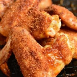 Baked chicken wings with dry rub stacked up on a wire rack.