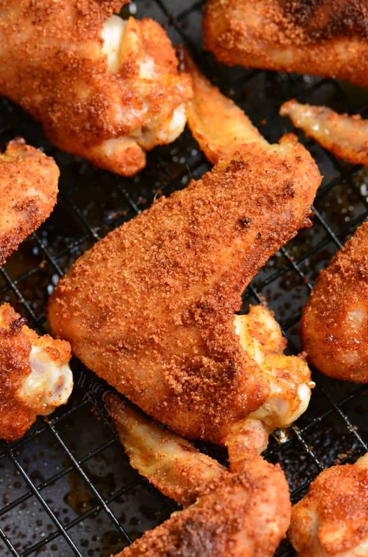 Baked chicken wings with a dry rub on a wire rack.