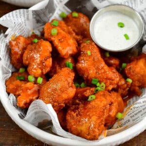 boneless buffalo wings in a plate lined with newspaper food liner.