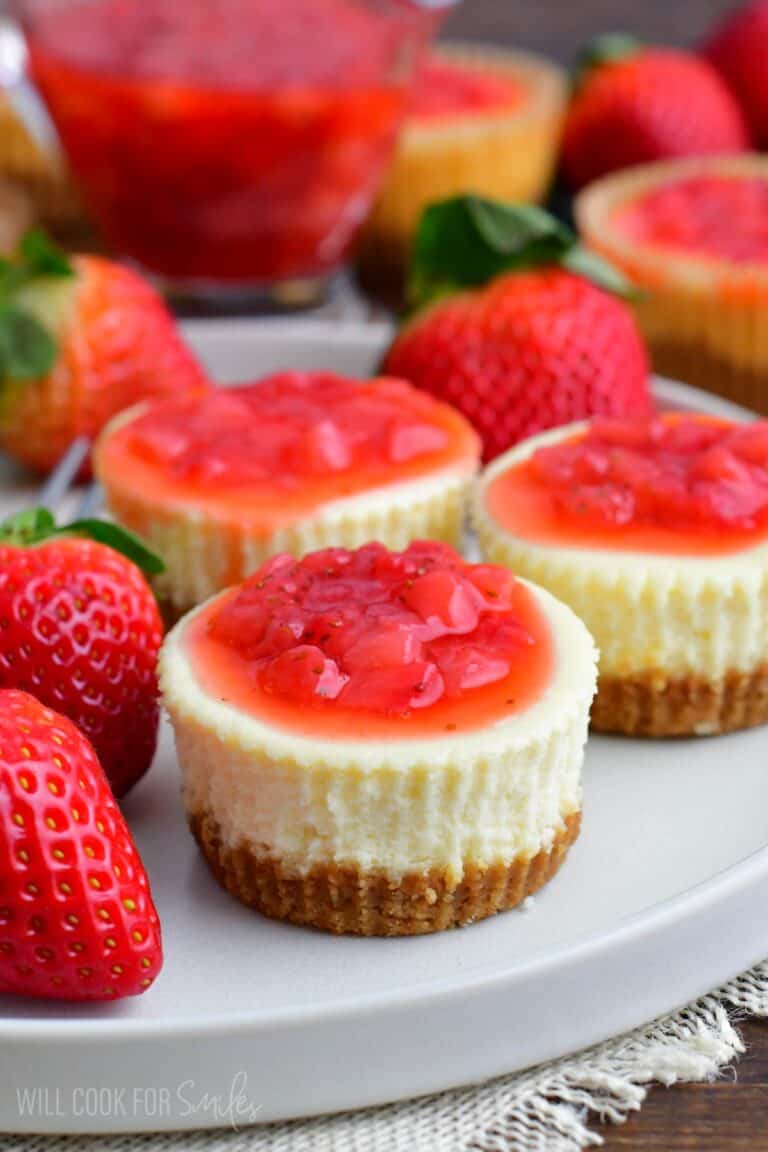 three mini cheesecakes on the plate topped with strawberry topping.